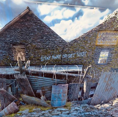 An in-game image of a ramshackle Cumbrian building, surrounded by barbed wire. It is an old broken mining company.
The words ‘STAY AWAY OR GET SHOT’ have been painted on the side of the building.
Ahh. Happy memories.