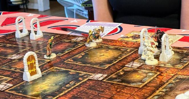 A HeroQuest board game in progress, with doors (open and closed) scattered about and hero minis moving around the board. The barbarian mini is surrounded by skeletons.