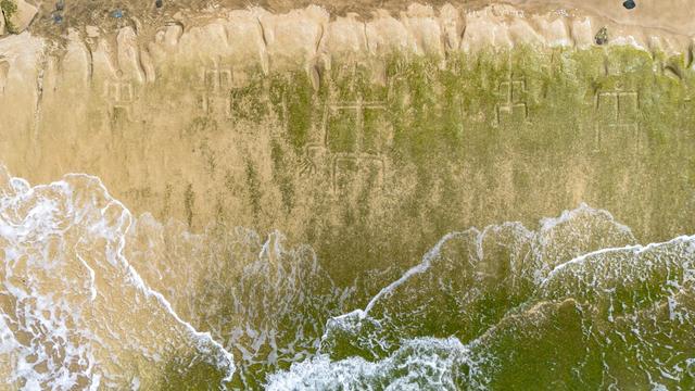 A drone view shows petroglyphs carved into the rock surface at Pokai Bay, July 22, 2025, in Waianae, Hawaii. (AP Photo/Mengshin Lin)