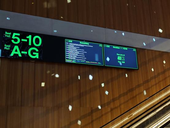 A picture of the infobeamer screens next to the escalator at 39c3, the text on one of the screens says see you at 40c3, day -360.