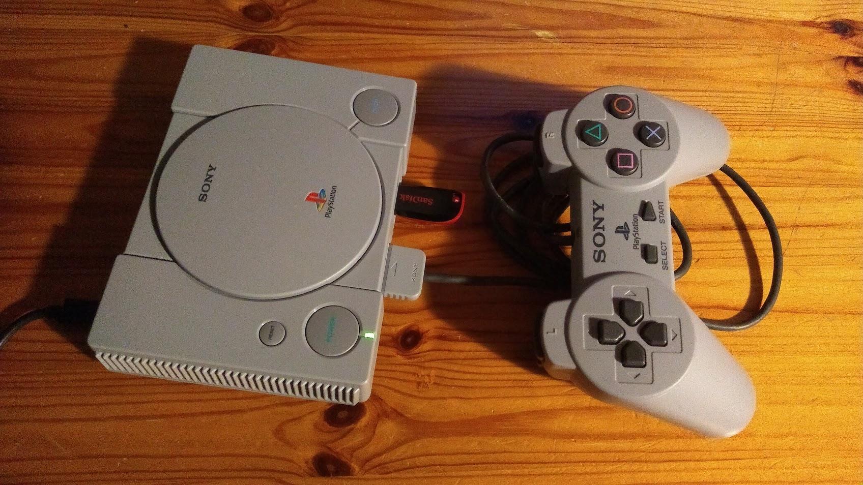 A PlayStation Classic with a replica PS1 controller and a SanDisk USB stick connected to the front ports